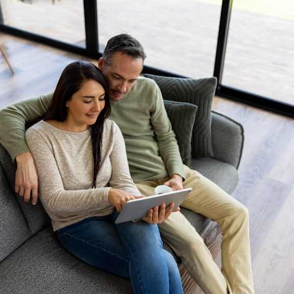 a man and woman sitting on a couch looking at a tablet at Creekside Canopy, Charlotte, NC 28212