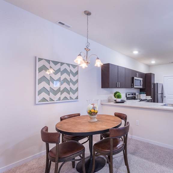 a dining room with a table and chairs next to a kitchen at aventura at towne centre, ellisville, missouri
