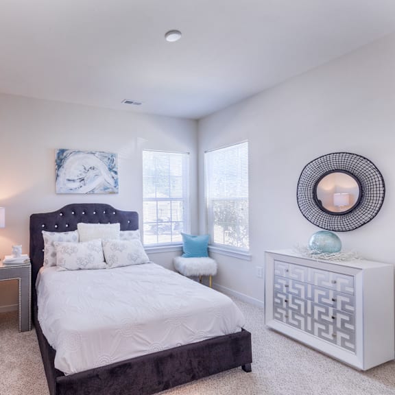 a bedroom with a bed and two windows at aventura at towne centre, ellisville
