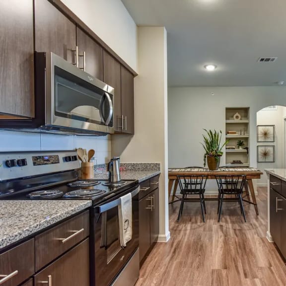 Thumbnail 3 of 11 Galley kitchen with stainless steel appliances and dining area at High Point Preserve Apartments, Austin