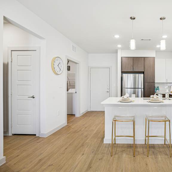 Thumbnail 15 of 37 A kitchen with a bar area and four stools. at ThreeTwenty at the Vybe Apartments, Texas, 78640