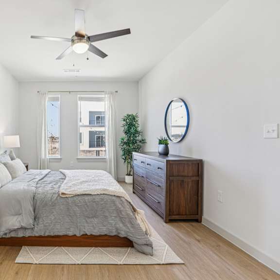 Thumbnail 19 of 37 A bedroom with a bed, nightstand, and a ceiling fan. at ThreeTwenty at the Vybe Apartments, Texas