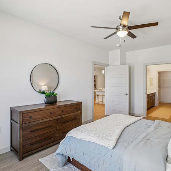 Thumbnail 21 of 37 A bedroom with a bed, dresser, and mirror. at ThreeTwenty at the Vybe Apartments, Kyle, TX