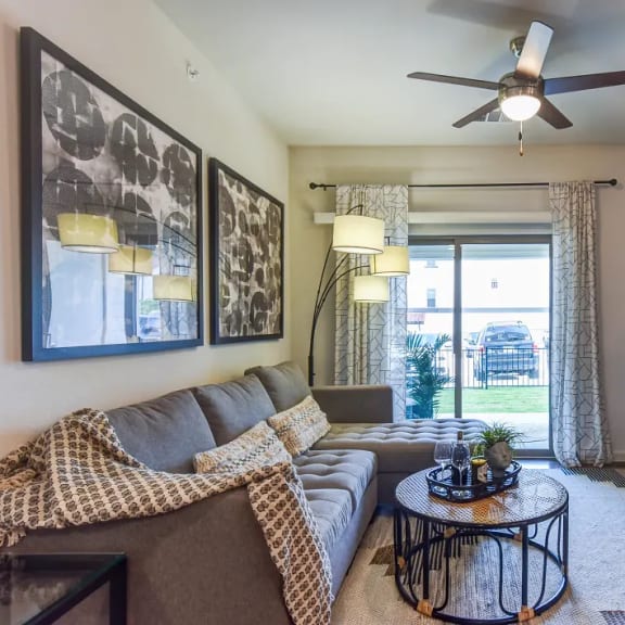 Thumbnail 4 of 11 Living room with gray sectional sofa and patterned rug at High Point Preserve Apartments, Texas, 78724