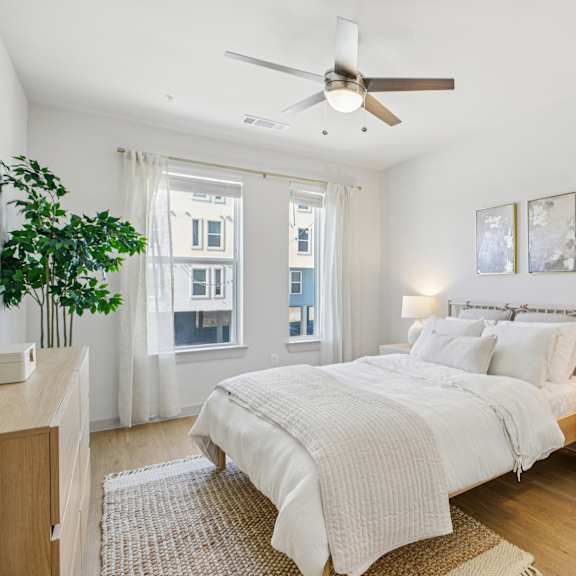 Thumbnail 23 of 37 A bedroom with a large bed and a ceiling fan. at ThreeTwenty at the Vybe Apartments, Kyle