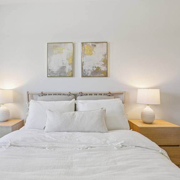 Thumbnail 27 of 37 A bed with white bedding and two white lamps on either side. at ThreeTwenty at the Vybe Apartments, Kyle, Texas