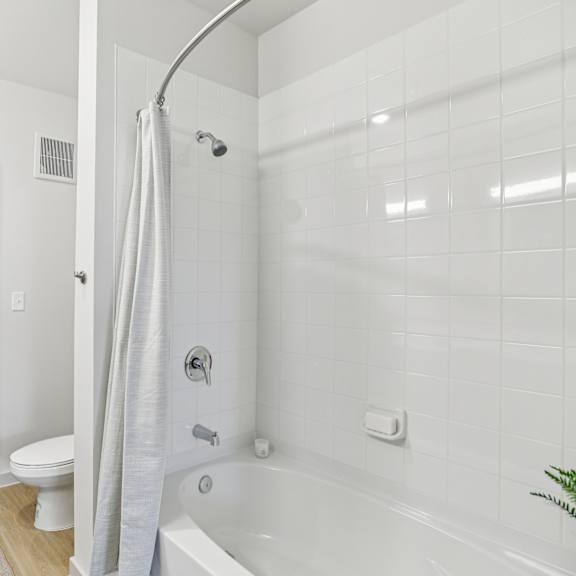 Thumbnail 29 of 37 A white bathroom with a white tub and toilet. at ThreeTwenty at the Vybe Apartments, Kyle, TX
