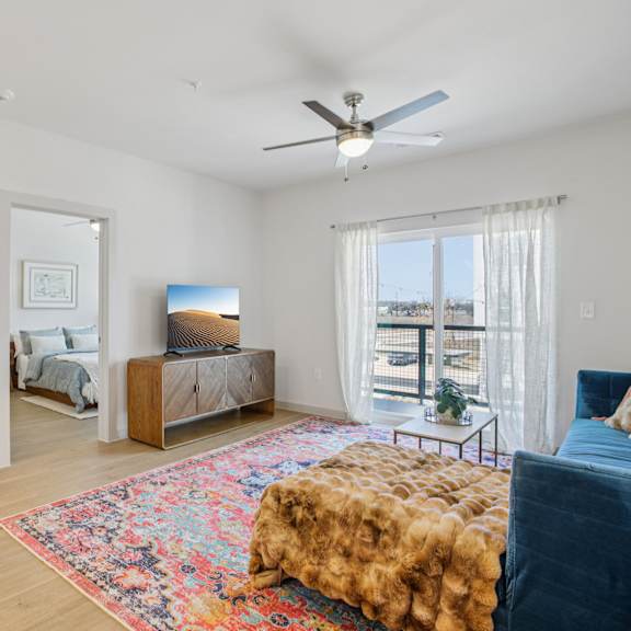 Thumbnail 5 of 37 A bedroom with a bed, a chair, and a rug. at ThreeTwenty at the Vybe Apartments, Kyle, TX