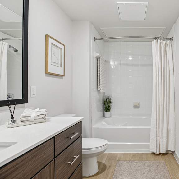 Thumbnail 35 of 37 A white bathroom with a toilet, sink, and bathtub. at ThreeTwenty at the Vybe Apartments, Texas, 78640