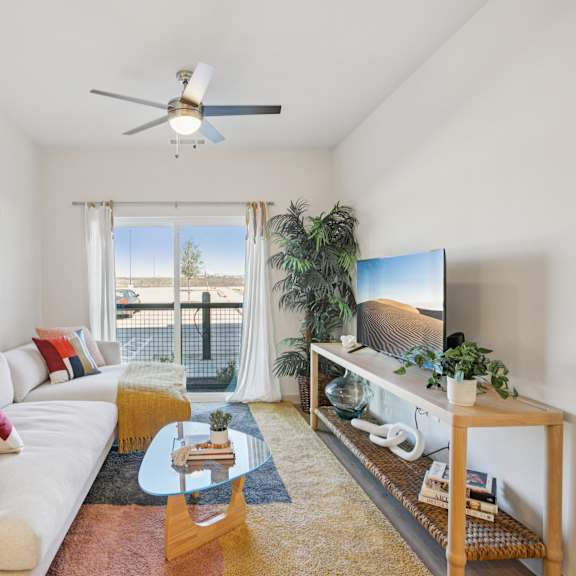 Thumbnail 5 of 23 A living room with a white couch, a wooden coffee table, and a flat screen TV. at ThreeTwenty at the Vybe Apartments, Texas, 78640