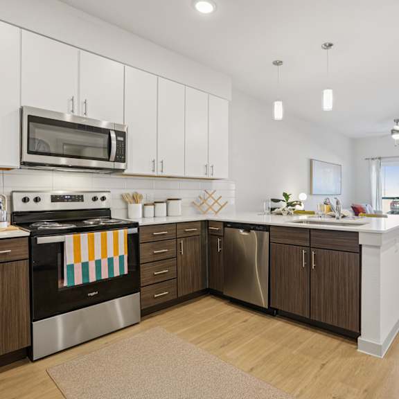 Thumbnail 8 of 23 A modern kitchen with wooden cabinets and stainless steel appliances. at ThreeTwenty at the Vybe Apartments, Kyle, TX
