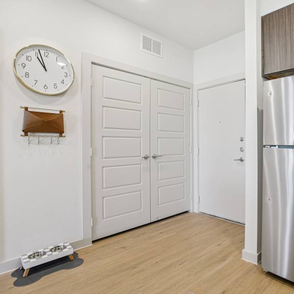 Thumbnail 13 of 23 A kitchen with a clock on the wall and a refrigerator at ThreeTwenty at the Vybe Apartments, Kyle