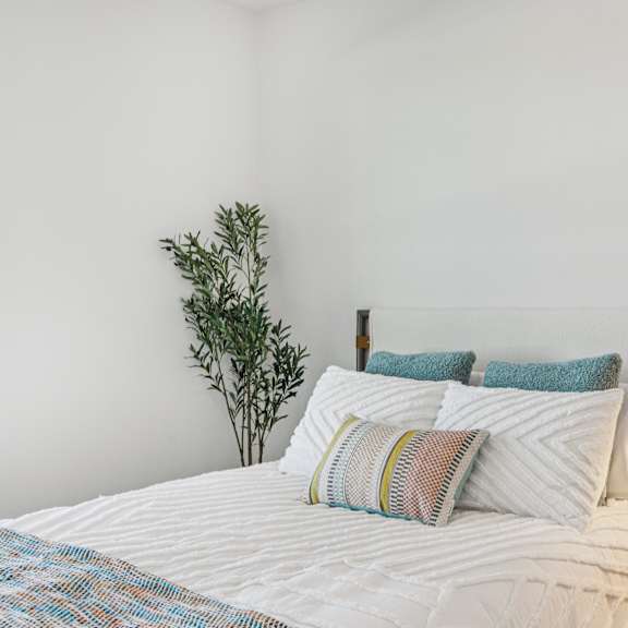 Thumbnail 18 of 23 A bed with a white comforter and a white pillow with a blue pillow case on it. at ThreeTwenty at the Vybe Apartments, Kyle