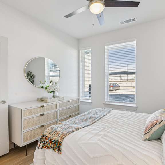 Thumbnail 19 of 23 A bedroom with a bed, dresser, mirror, and window at ThreeTwenty at the Vybe Apartments, Texas