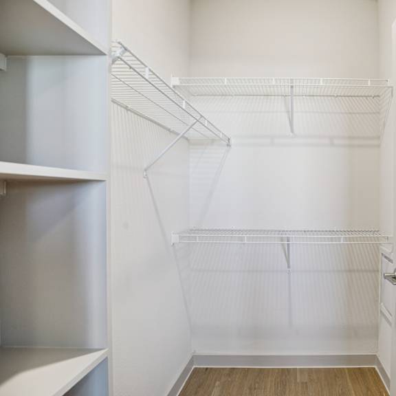 Thumbnail 20 of 23 A white closet with shelves and a wooden floor at ThreeTwenty at the Vybe Apartments, Kyle, TX, 78640