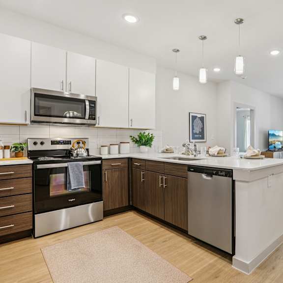Thumbnail 10 of 37 A modern kitchen with stainless steel appliances and wooden cabinets at ThreeTwenty at the Vybe Apartments, Texas, 78640
