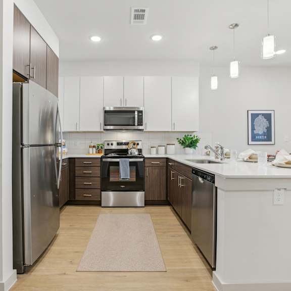 Thumbnail 11 of 37 A modern kitchen with a refrigerator, microwave, and oven. at ThreeTwenty at the Vybe Apartments, Texas, 78640