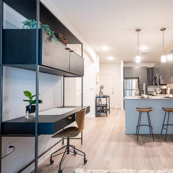 Thumbnail 9 of 15 a home office with a desk and stools next to a kitchen with a breakfast bar at Three Hills, Austin, TX