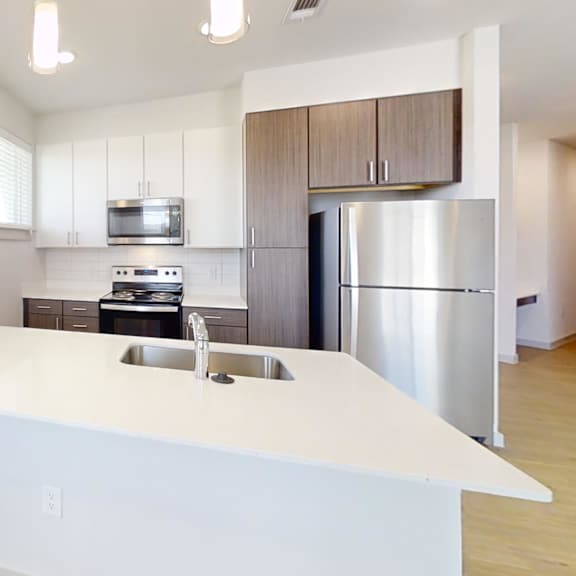 Thumbnail 3 of 14 A modern kitchen with a white countertop and stainless steel appliances. at ThreeTwenty at the Vybe Apartments, Kyle, TX, 78640