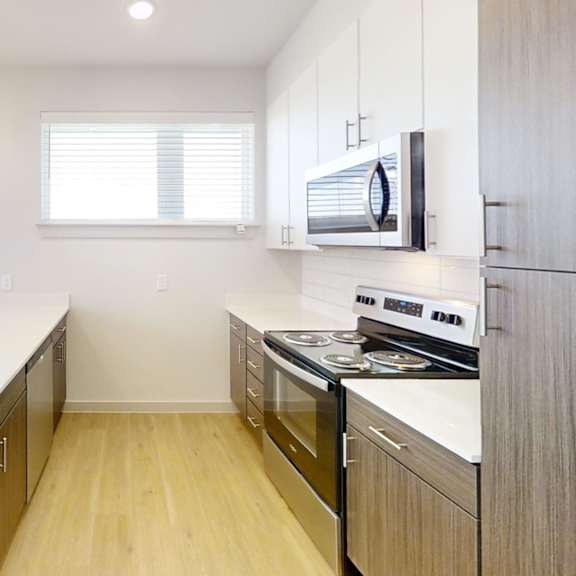 Thumbnail 4 of 14 A modern kitchen with wooden cabinets and stainless steel appliances. at ThreeTwenty at the Vybe Apartments, Kyle, TX