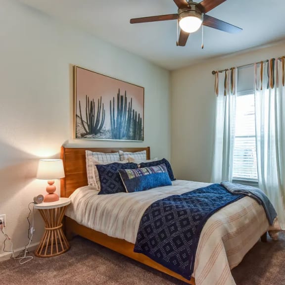 Thumbnail 9 of 11 Bedroom with wood bed frame and blue bedding accents 1 at High Point Preserve Apartments, Austin, Texas