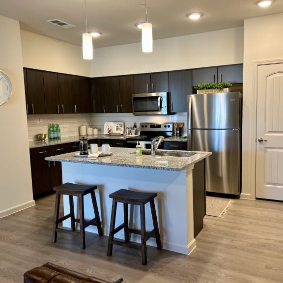 Thumbnail 2 of 16 Modern kitchen with island seating and dark cabinetry 1 at High Point Preserve Apartments, Texas, 78724