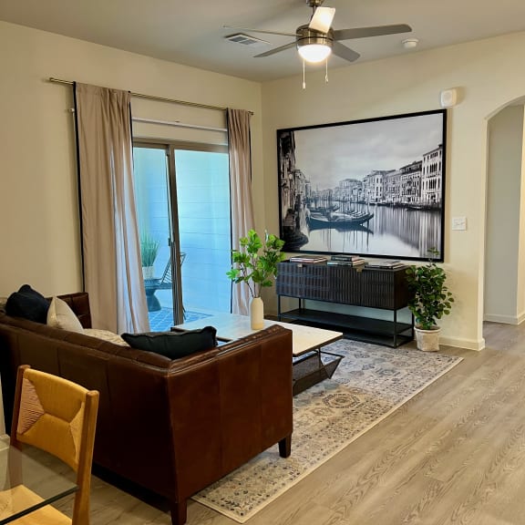 Thumbnail 3 of 16 Living room with brown leather sofa and tv console 1 at High Point Preserve Apartments, Austin, TX 78724