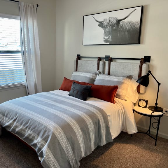 Thumbnail 7 of 16 Bedroom with highland cow artwork and striped bedding 1 at High Point Preserve Apartments, Austin