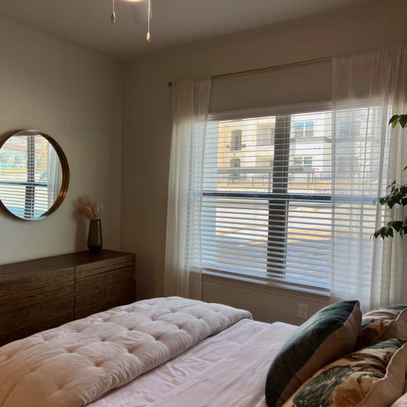 Thumbnail 12 of 16 Bedroom with round mirror and wood dresser at High Point Preserve Apartments, Austin, 78724