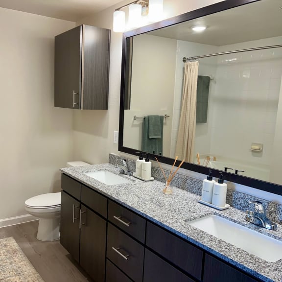 Thumbnail 14 of 16 Double vanity bathroom with speckled granite and mirror at High Point Preserve Apartments, Austin