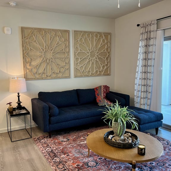 Thumbnail 5 of 13 Living room with navy sectional sofa and geometric wall art at High Point Preserve Apartments, Austin, Texas