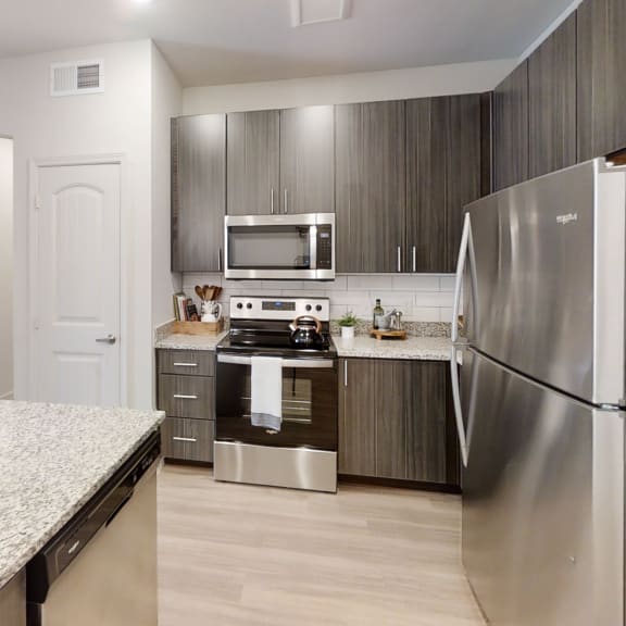 Thumbnail 3 of 8 a kitchen with stainless steel appliances and granite countertops