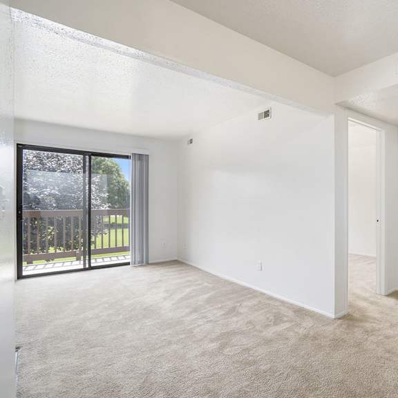 Thumbnail 5 of 11 A spacious living room with a carpeted floor and sliding glass doors leading to a balcony at Apple Ridge Apartments, Michigan, 49534