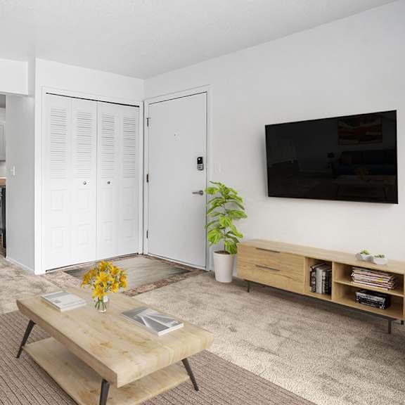 Thumbnail 4 of 5 A living and dining room with a blue couch, a wooden coffee table, and a flat screen TV mounted on the wall at Apple Ridge Apartments in Walker, MI