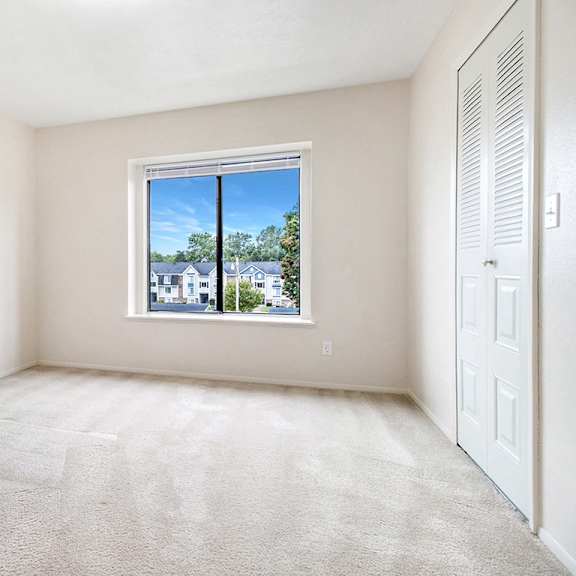 Thumbnail 12 of 13 A bedroom with a carpeted floor and a window at Arbor Lakes Apartments in Elkhart, IN
