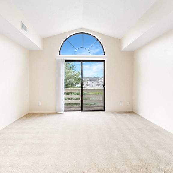 Thumbnail 4 of 13 A living room with a large window and a cathedral ceiling at Arbor Lakes Apartments in Elkhart, IN