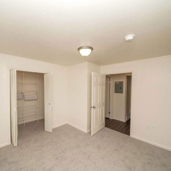 Thumbnail 8 of 8 an empty living room with a closet and a door to a bathroom  at Arbor Lakes Apartments, Elkhart, Indiana