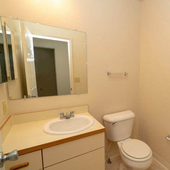 Thumbnail 7 of 11 a bathroom with a toilet and a sink and a mirror at Autumn Lakes Apartments and Townhomes, Mishawaka, Indiana