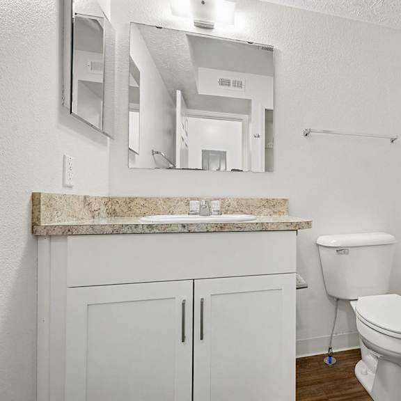Thumbnail 13 of 22 A white bathroom with a marble counter top and a toilet.