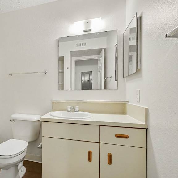 Thumbnail 14 of 22 A white bathroom with a toilet, sink, and mirror.