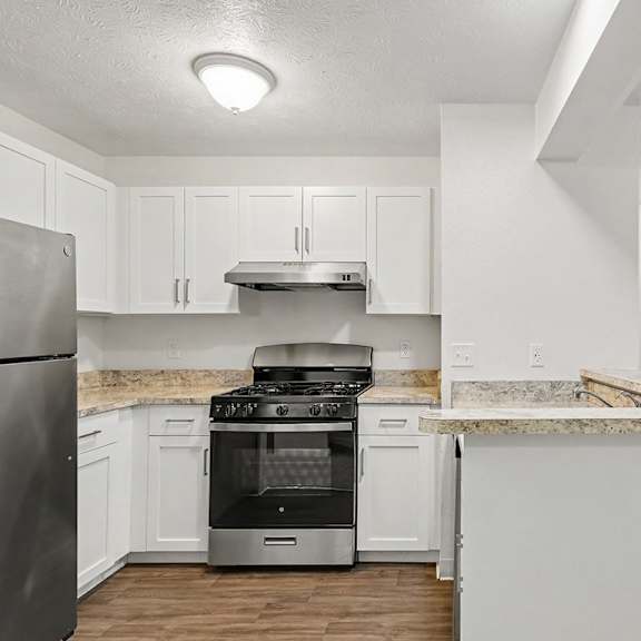 Thumbnail 10 of 22 A kitchen with white cabinets and a stainless steel refrigerator.