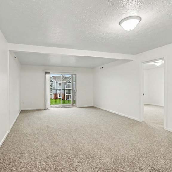 Thumbnail 4 of 22 A spacious empty room with carpeted floor and white walls.