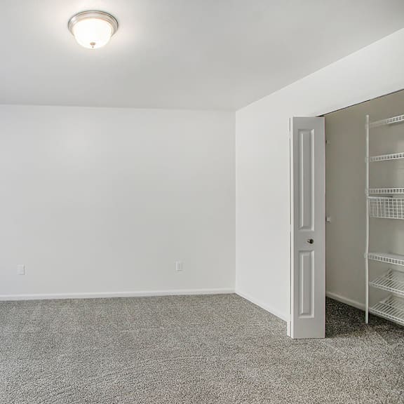 Thumbnail 12 of 16 A bedroom with a carpeted floor, a window with blinds, and a walk-in closet with organizers at Autumn Lakes Apartments and Townhomes, Mishawaka, 46544