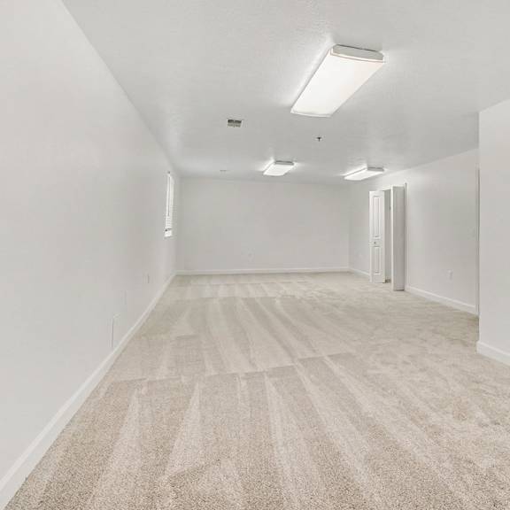 Thumbnail 19 of 20 A basement recreation room with carpeted flooring and white walls at Autumn Lakes Apartments and Townhomes in Mishawaka, IN