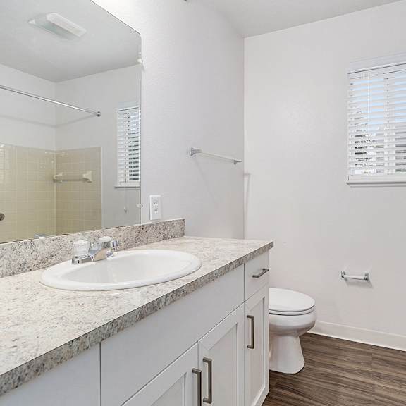 Thumbnail 7 of 12 A white bathroom with a window, sink, toilet, and bathtub at Autumn Lakes Apartments and Townhomes, Mishawaka, 46544
