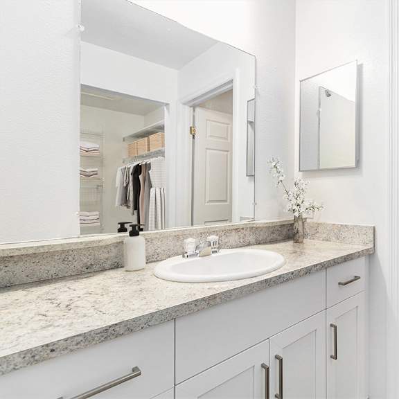 Thumbnail 10 of 12 A white bathroom with a sink, large mirror and countertop, along with a bathtub at Autumn Lakes Apartments and Townhomes, Mishawaka, 46544