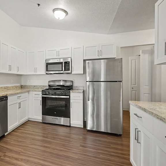 Thumbnail 7 of 18 A kitchen with white cabinets and stainless steel appliances.