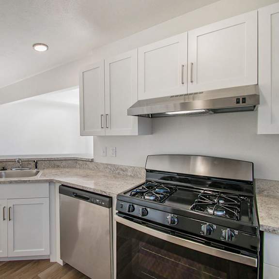 Thumbnail 7 of 12 A kitchen with white cabinets and a stainless steel gas stove and dishwasher at Brentwood Park Apartments, La Vista, 68128