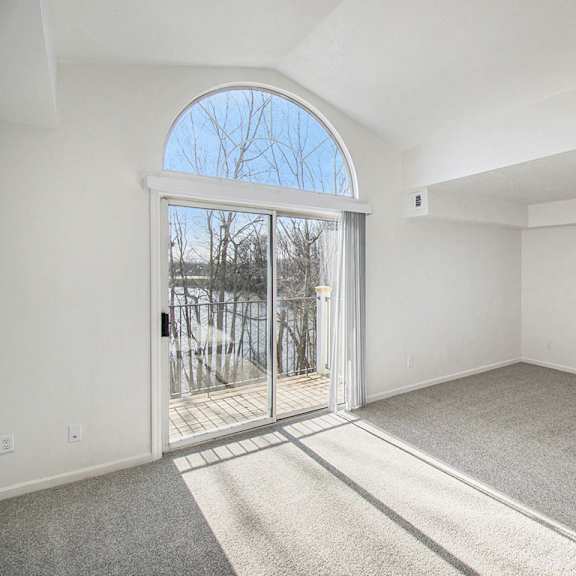 Thumbnail 4 of 12 An enlarged living room with cathedral ceiling and a slider to a balcony at Brentwood Park Apartments, La Vista, Nebraska