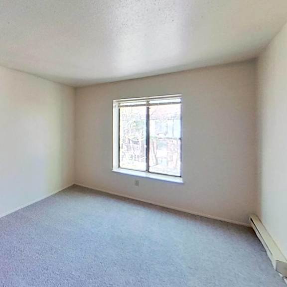 Thumbnail 10 of 10 A spacious bedroom with a window and carpeted floor at Briarwood Apartments in Benton Harbor, MI